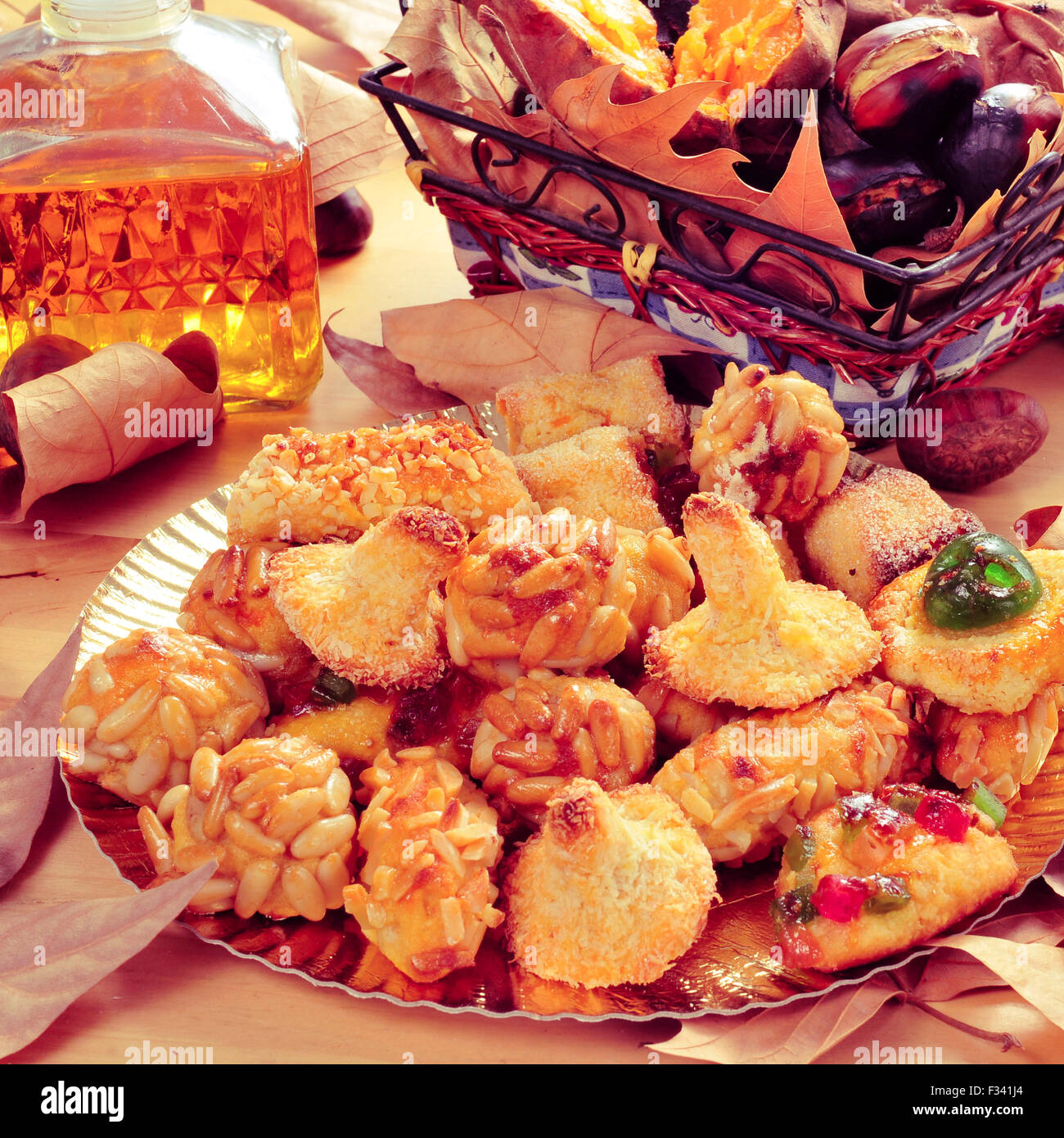 Nahaufnahme einer Platte mit Panellets, einige geröstete Kastanien und Süßkartoffeln in einen Korb und süßer Wein in einer Glasflasche, Eiterung Stockfoto