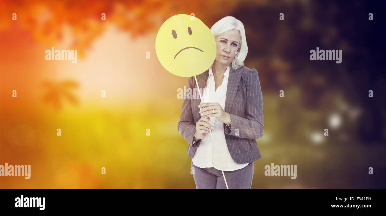 Zusammengesetztes Bild der Geschäftsfrau hält traurigen Smiley-Gesicht Stockfoto