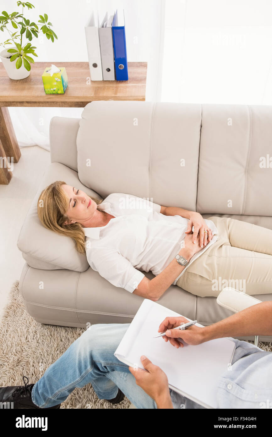 Unglückliche Frau liegend auf der Couch und im Gespräch mit Therapeuten Stockfoto