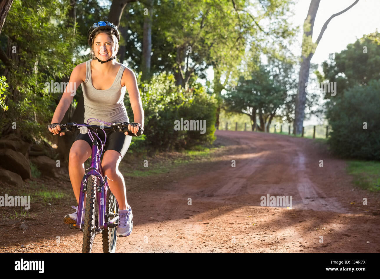 Lächelnde sportliche Brünette Mountainbiken auf Weg Stockfoto