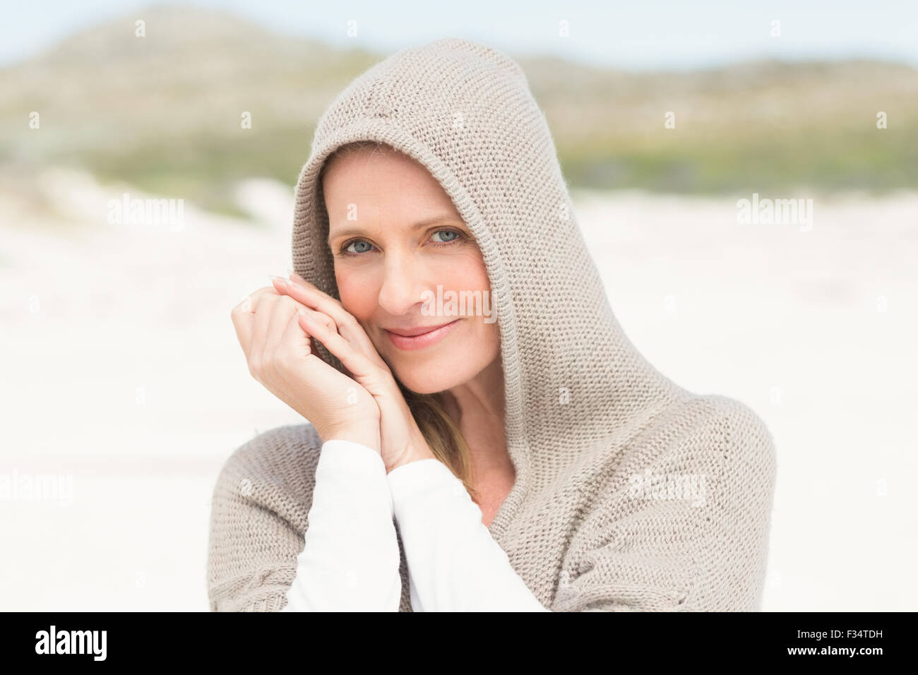 Lächelnde Frau aufstehen auf dem Sand mit Kapuze Stockfoto