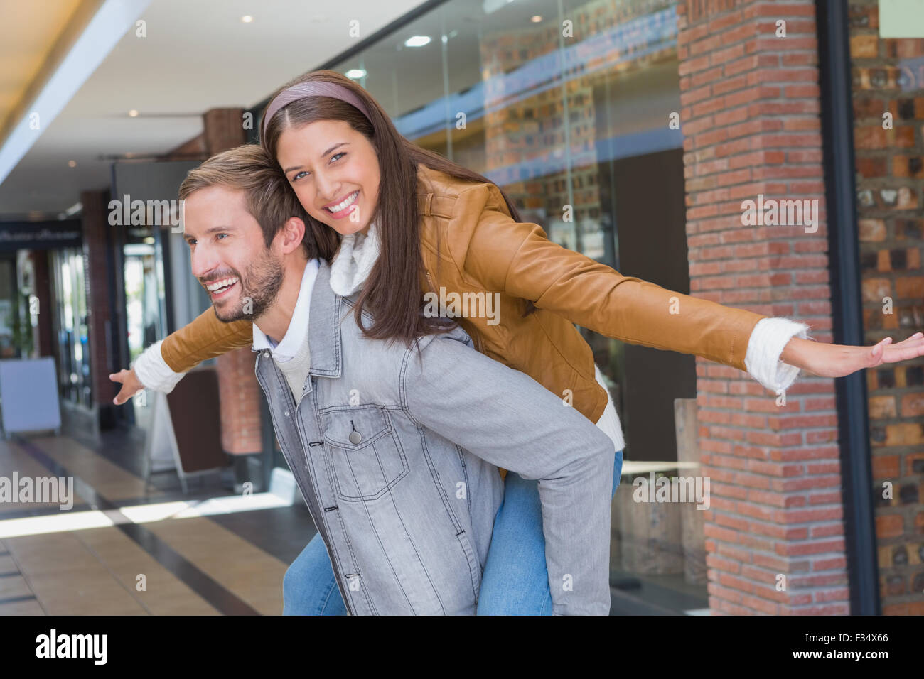 Junger Mann geben einer jungen Frau eine Schweinchen Fahrt Stockfoto