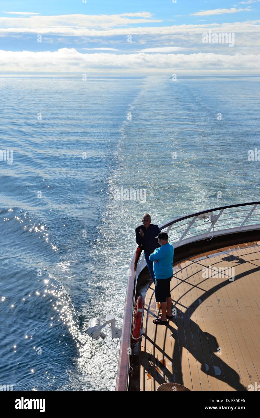 Zwei Männer stehen am Heck eines Kreuzfahrtschiffes mit Schiffen Gefolge in den Horizont verschwinden zu reden. Stockfoto