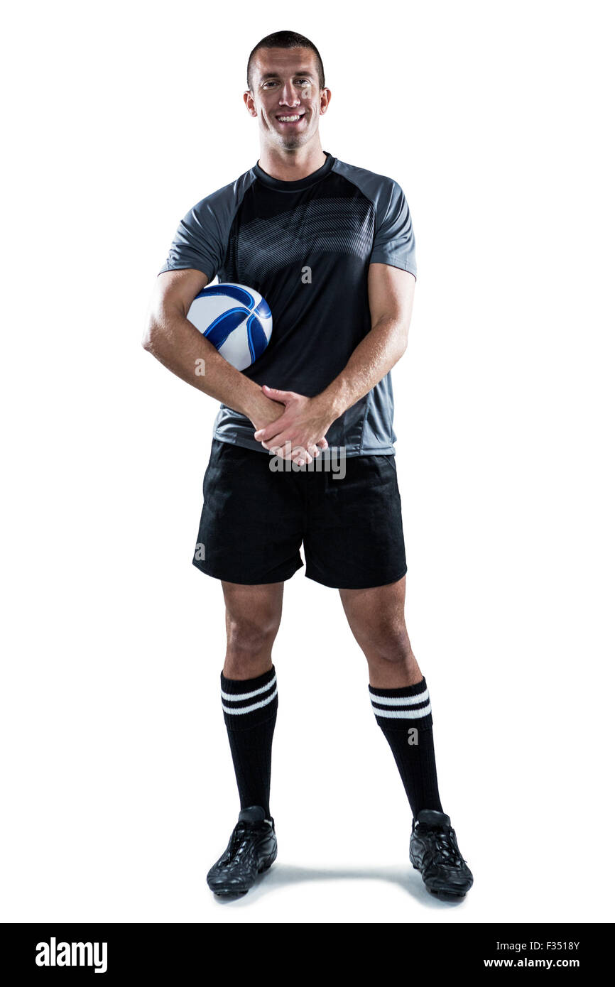 Rugby-Spieler aus schwarzem Jersey mit Ball mit den Händen umklammert lächelnd Stockfoto
