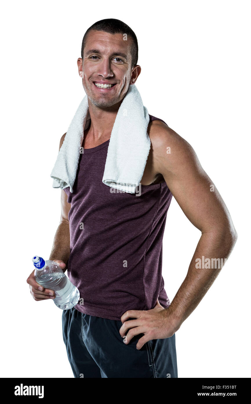 Lächelnder Mann mit Handtuch am Hals halten Wasser Flasche Stockfoto