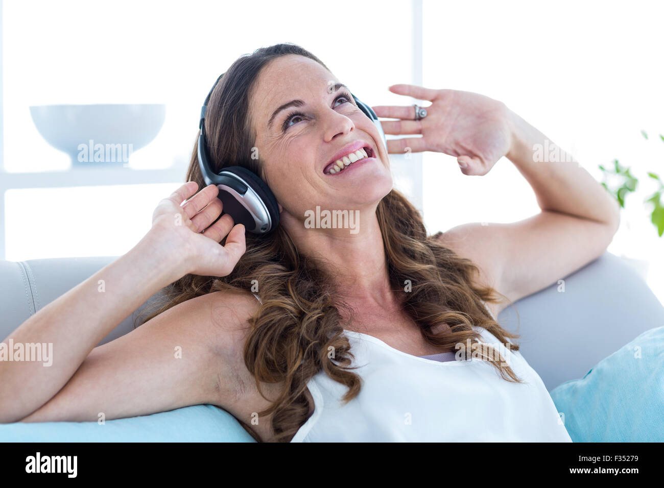 Lächelnde Frau Musik hören zu Hause Stockfoto