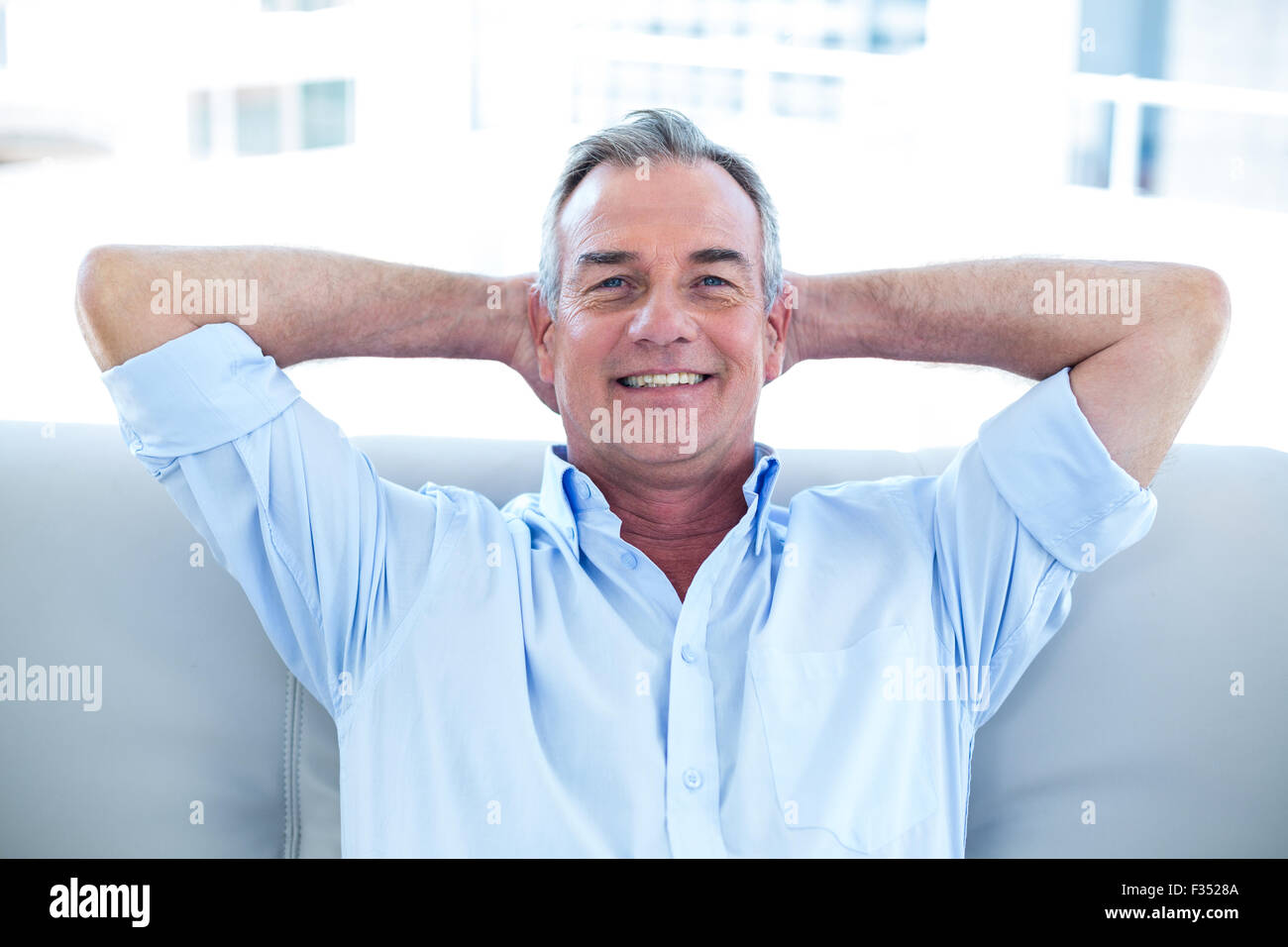 Glücklicher Mann mit Händen im Haar zu Hause sitzen Stockfoto