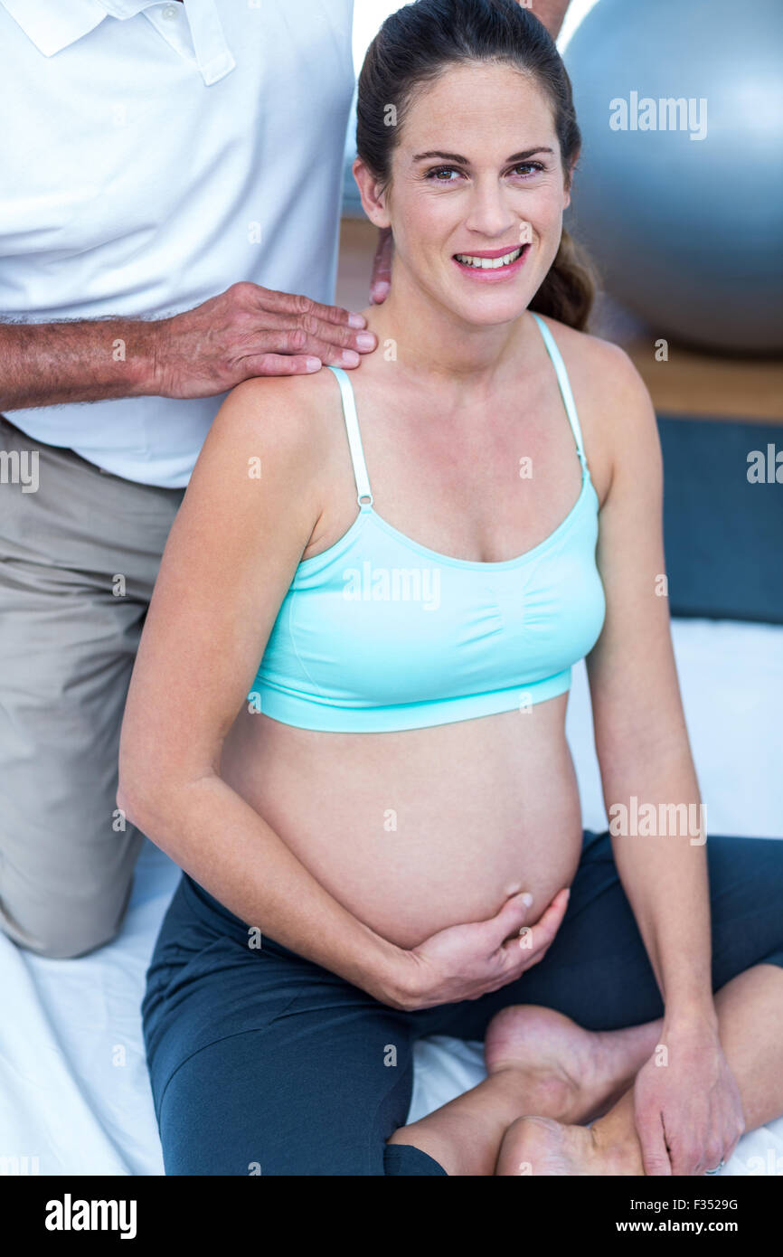 Glücklich schwanger Frau mit Trainer im Fitness-Studio Stockfoto