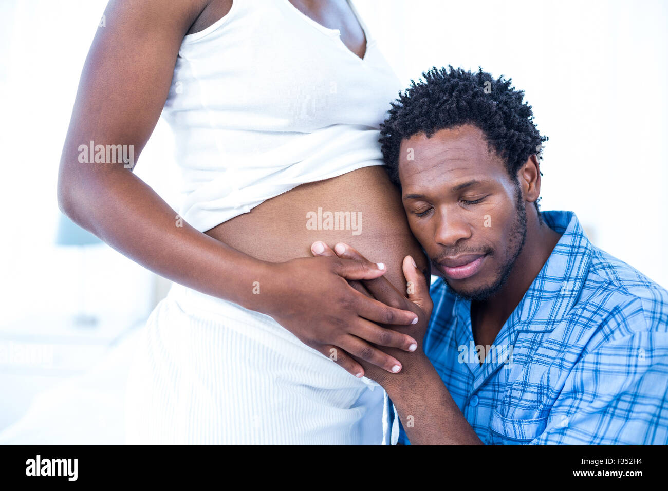 Mann mit geschlossenen Augen hören auf seine schwangere Frau Stockfoto