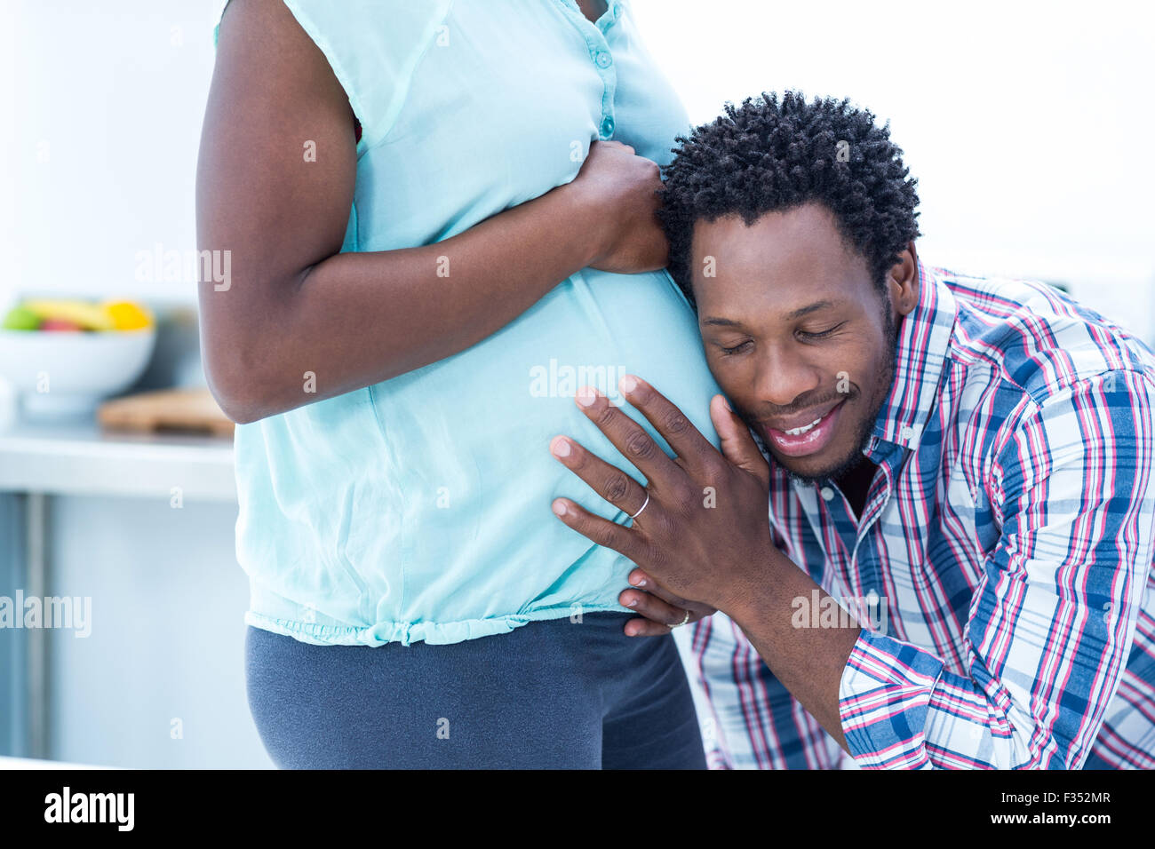 Glücklicher Ehemann mit geschlossenen Augen hören auf seine schwangere Frau Bauch Stockfoto