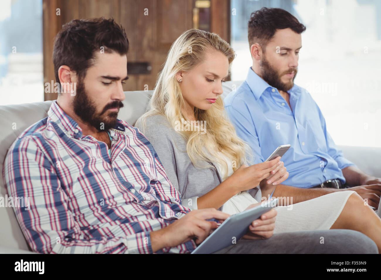 Geschäftsleute, die mit Technologien sitzend auf sofa Stockfoto