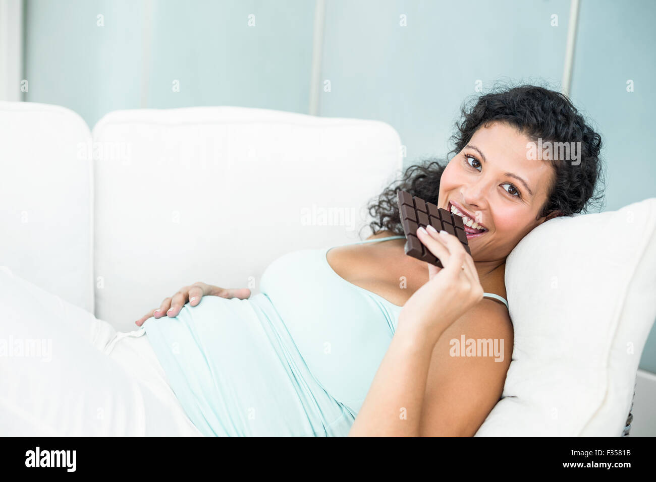 Glücklich schwanger Frau Tafel Schokolade essen Stockfoto