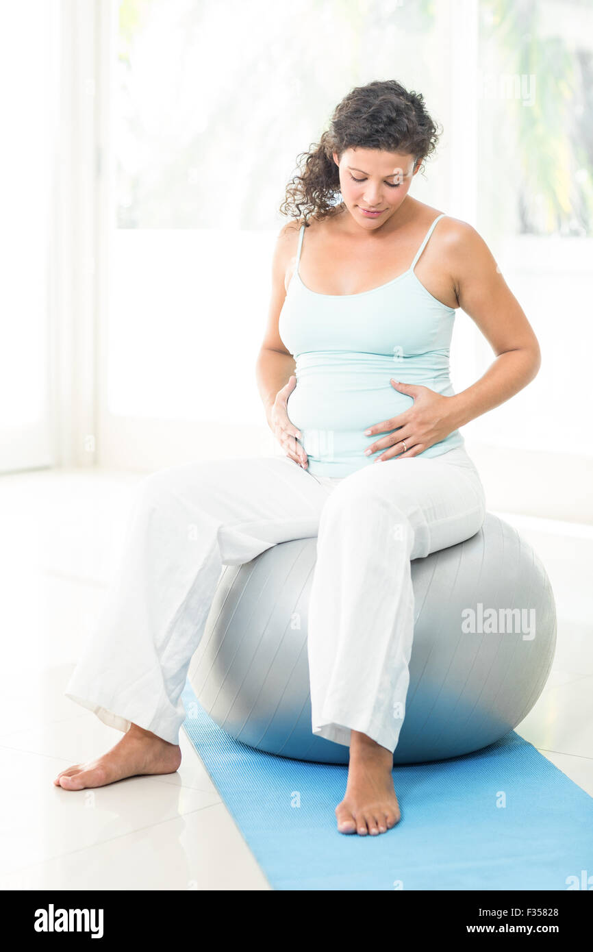 Schwangere Frau berühren ihren Bauch beim Sitzen auf einem Gymnastikball Stockfotografie Alamy