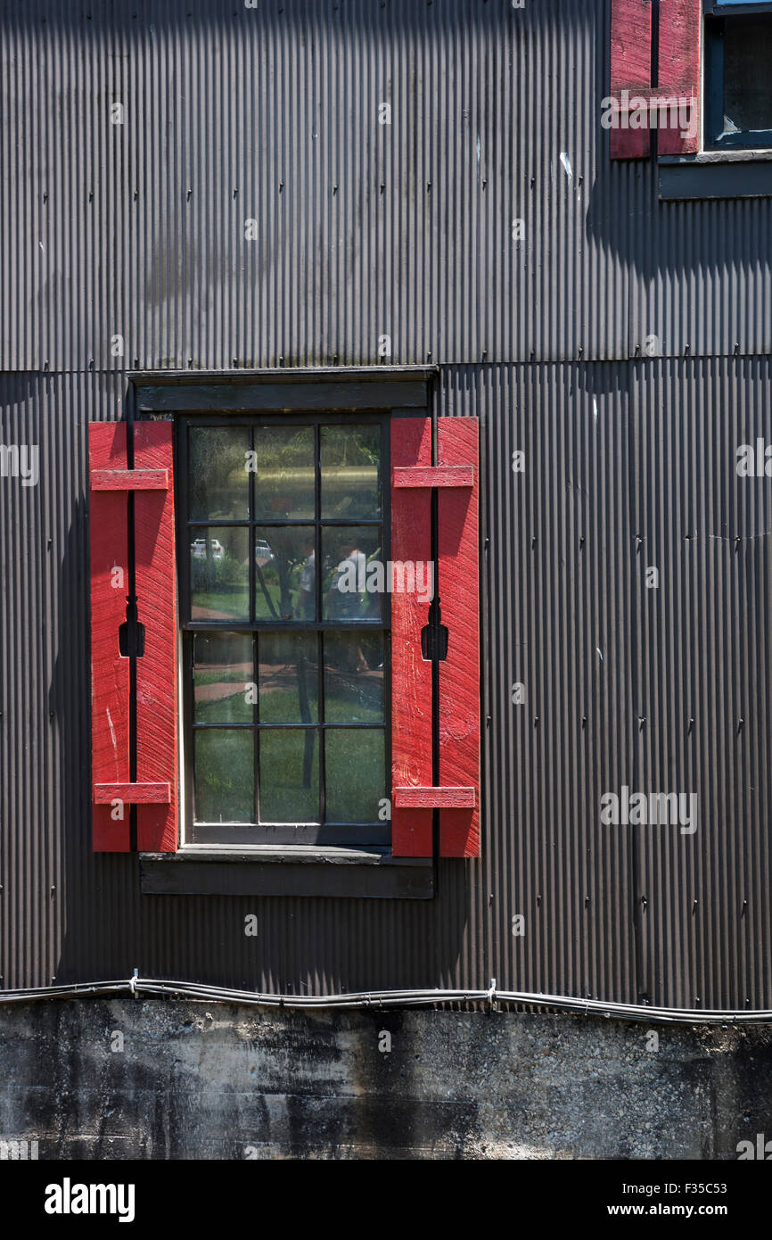 Außen grau Gebäude mit roten Fensterläden mit einer Whiskeyflasche Freisteller, Makers Mark Bourbon Brennerei, Kentucky, USA Stockfoto