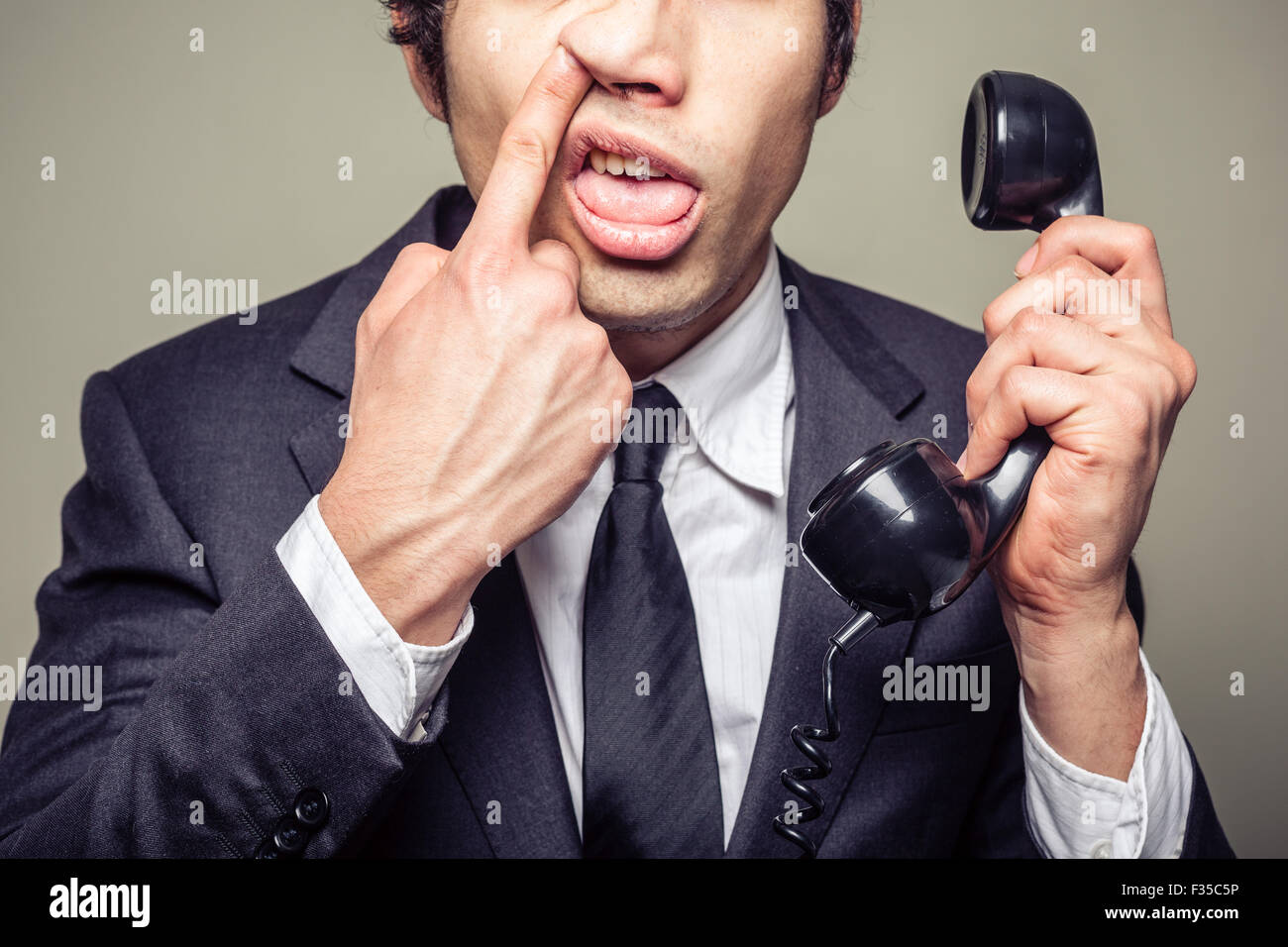 Inkompetente Jungunternehmer ist am Telefon und nimmt seine Nase Stockfoto