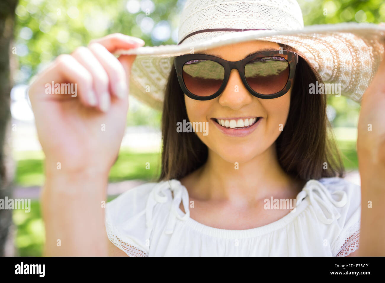 Glückliche junge Frau mit Sonnenbrille und Hut Stockfoto