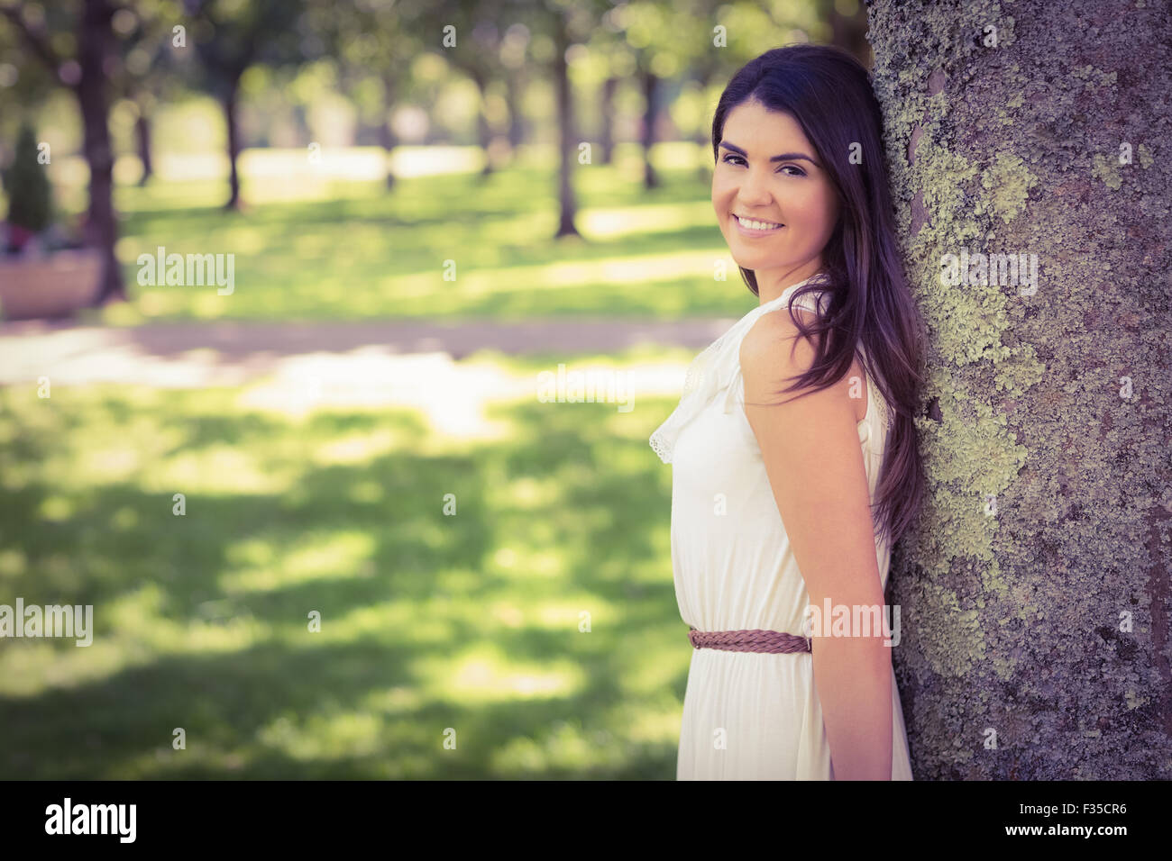 Porträt der stets gut gelaunte Frau stützte sich auf Baum Stockfoto