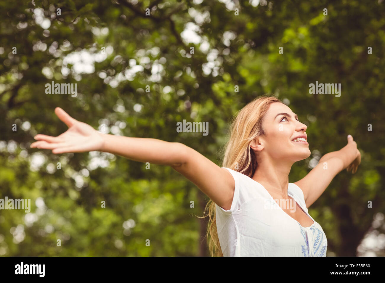Lächelnde Frau mit Park erhobenen Armen Stockfoto