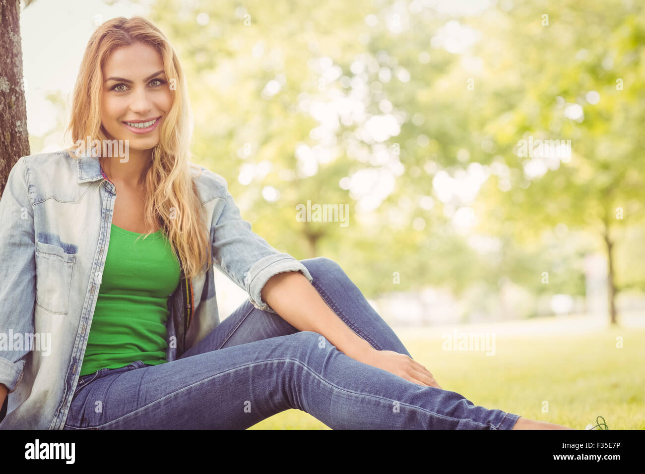 Porträt von glücklich Frau sitzt unter Baum Stockfoto