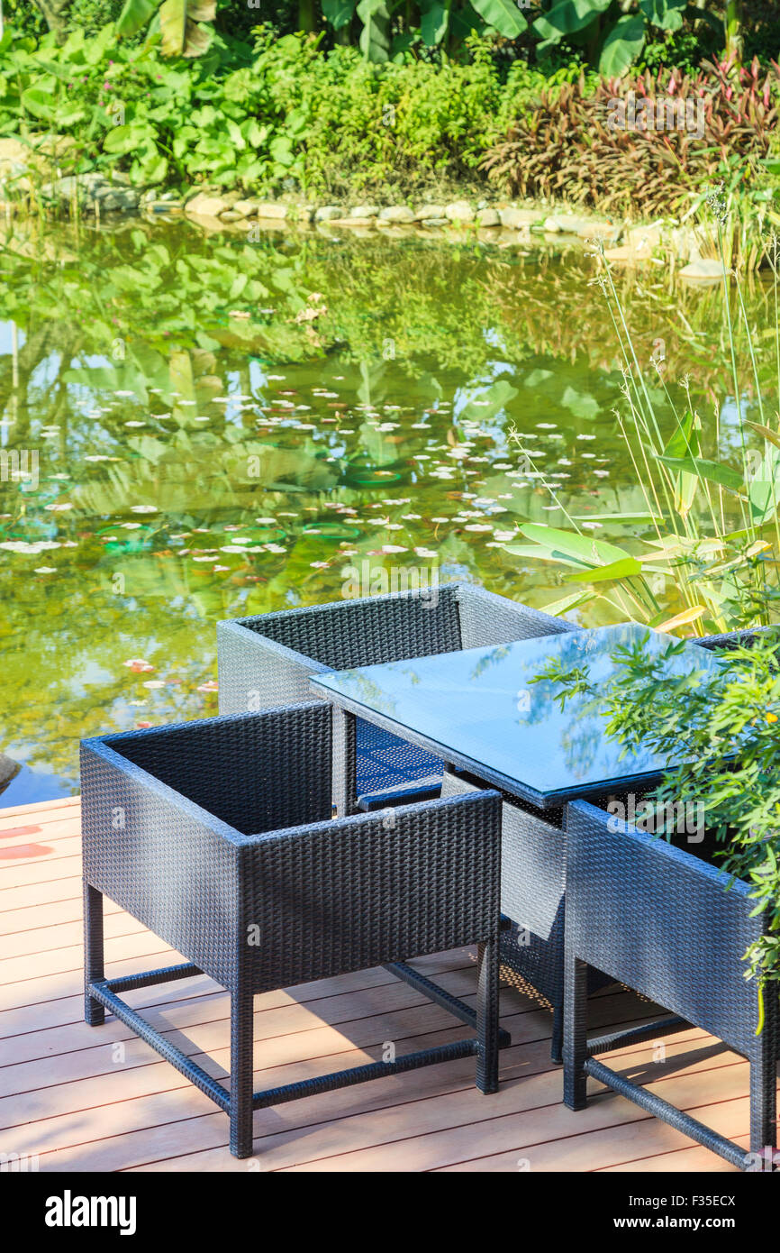 Ruhebereich mit Zuckerrohr Tisch und Sesseln, die durch einen Pool im Garten Stockfoto