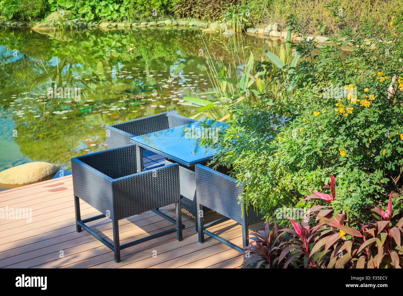 Ruhebereich mit Zuckerrohr Tisch und Sesseln, die durch einen Pool im Garten Stockfoto