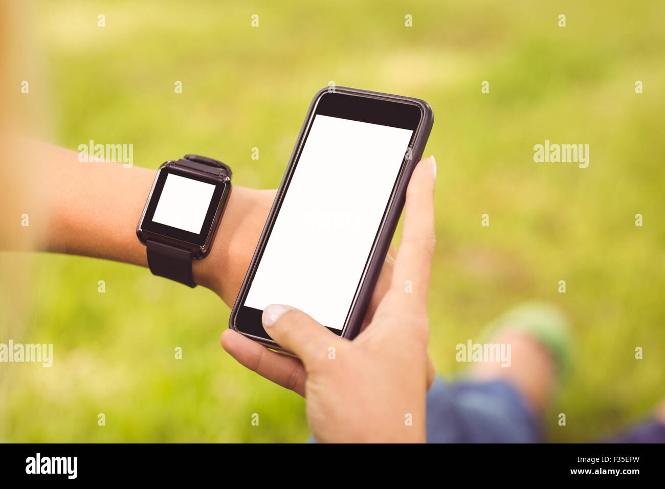 Abgeschnittenen Hände Smartwatch trägt und hält smartphone Stockfoto