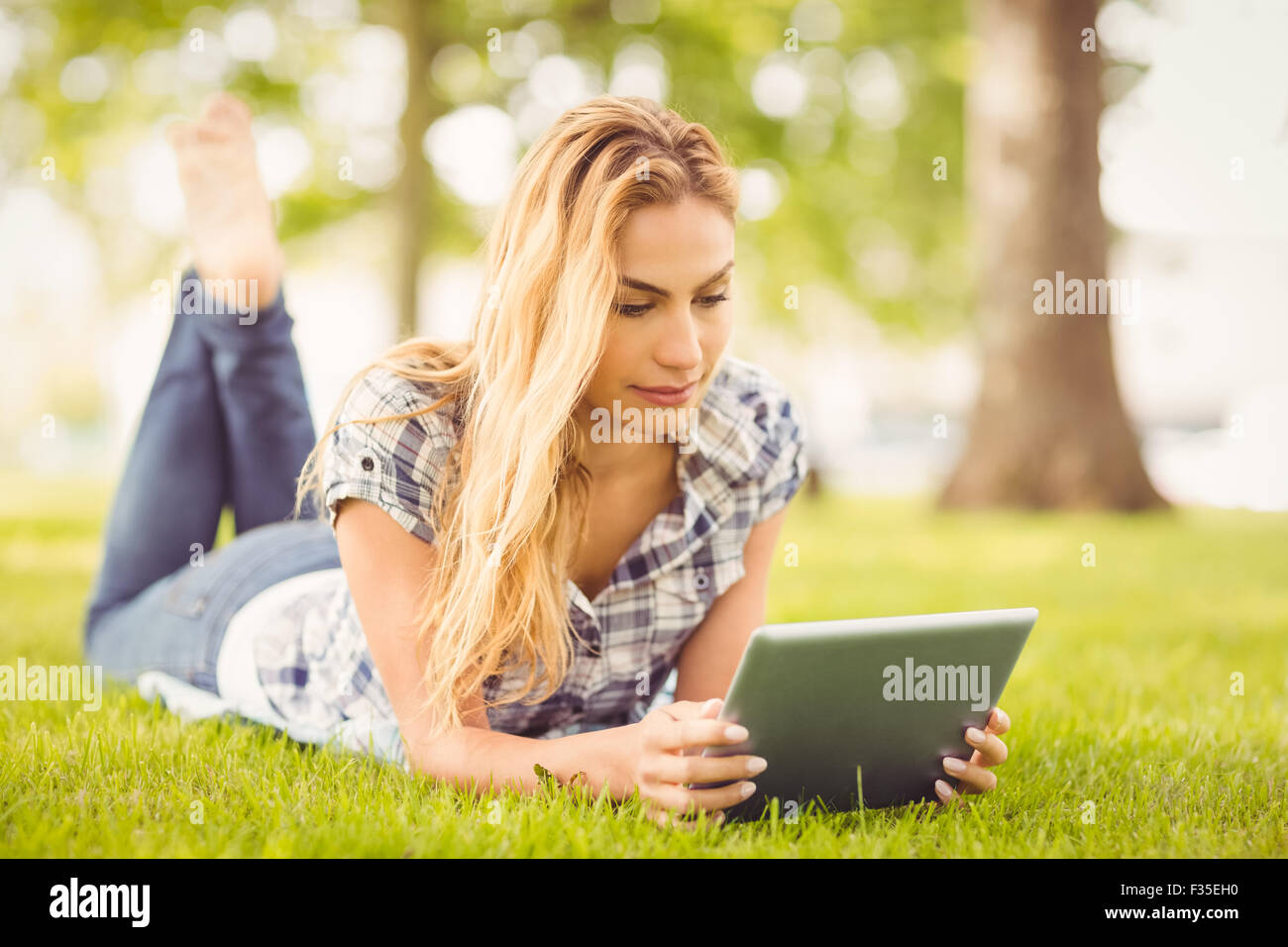 Frau mit digital-Tablette beim liegen auf dem Rasen Stockfoto