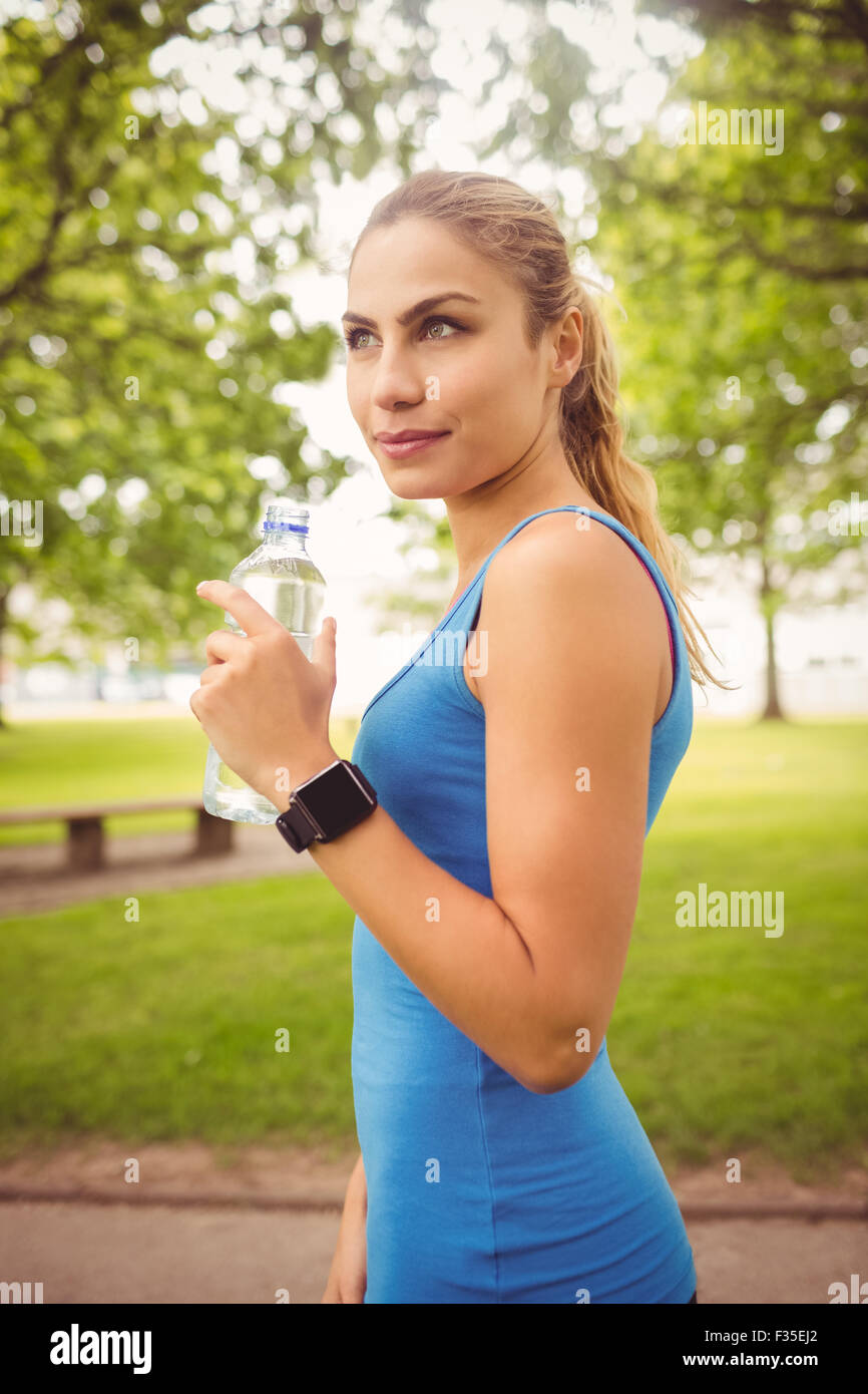 Lächelnde Frau Holding-Wasserflasche Jogger im park Stockfoto