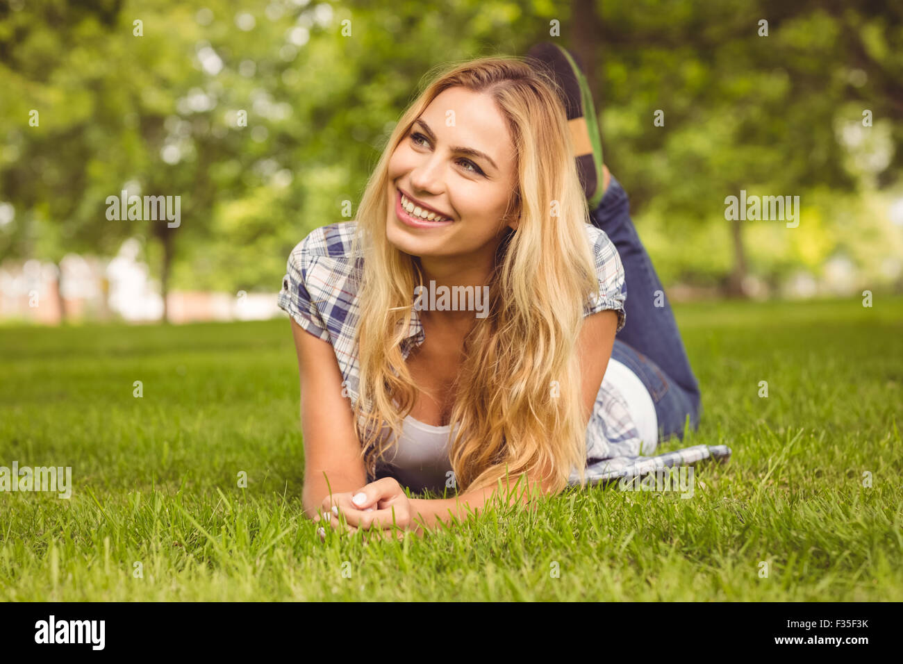 Lächelnde Frau liegend auf Vorderseite im park Stockfoto