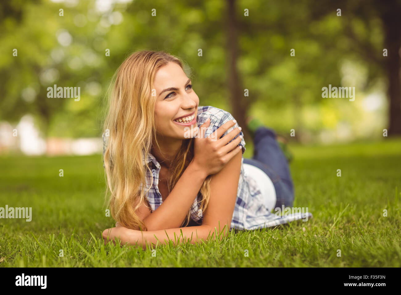 Stets gut gelaunte Frau liegend auf Vorderseite im park Stockfoto