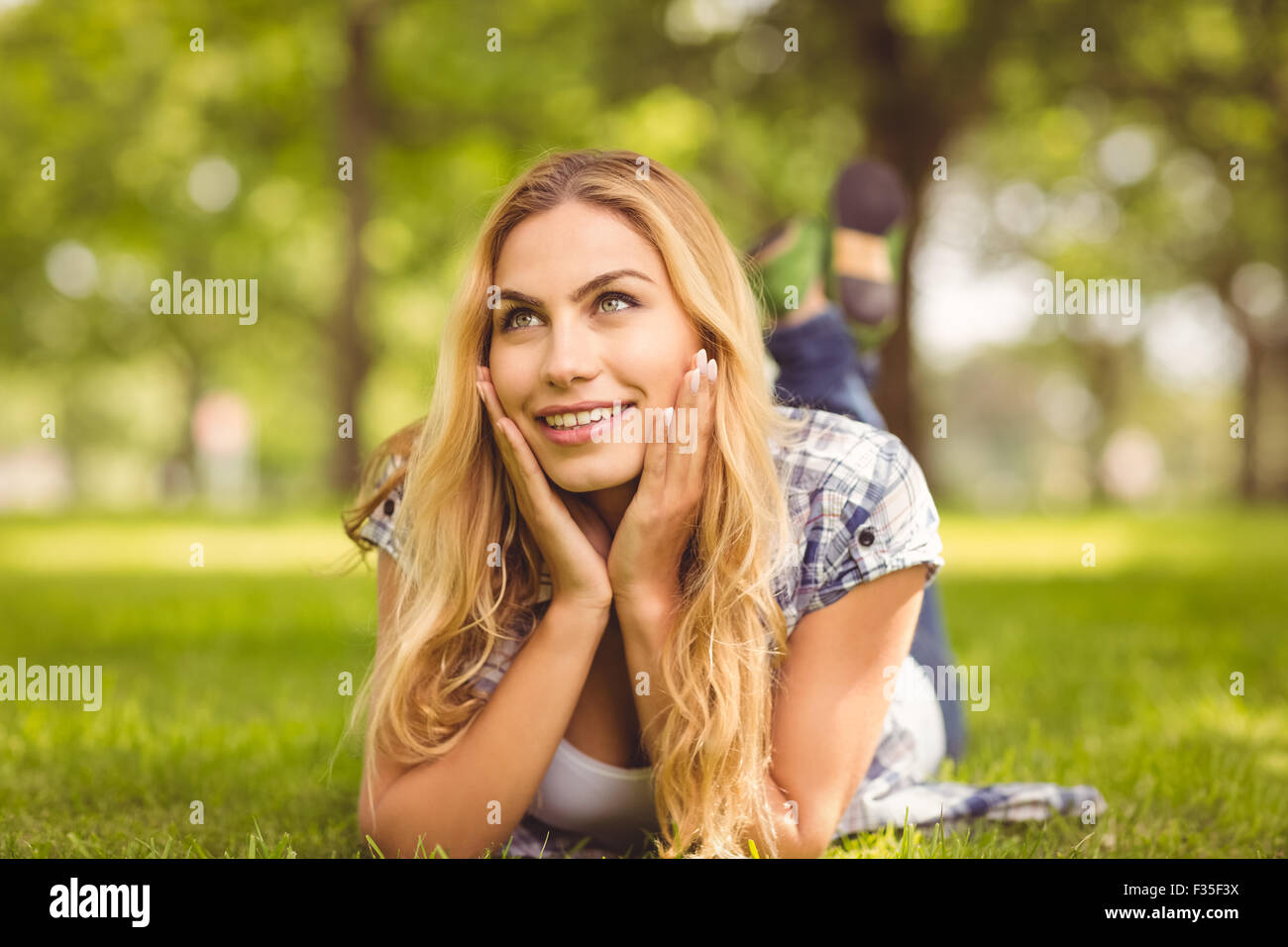 Lächelnde nachdenkliche Frau liegend auf Vorderseite Stockfoto