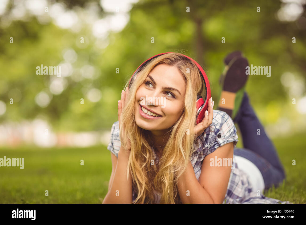 Gesamte Länge der lächelnde Frau anhören von Musik im park Stockfoto