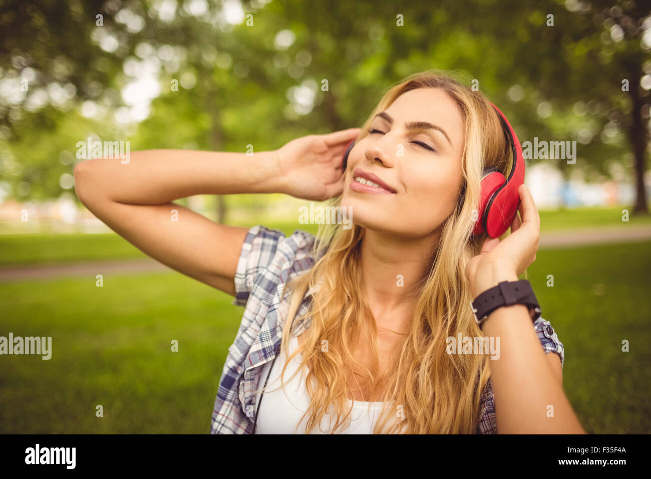 Lächelnde Frau genießen Musik mit Augen geschlossen im park Stockfoto