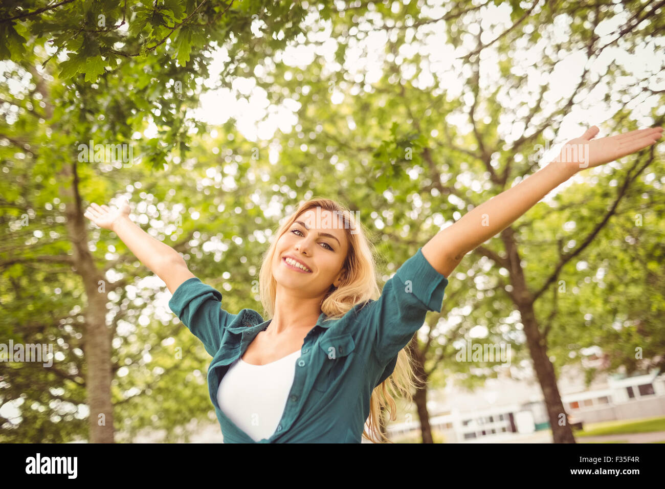 Portrait der schönen Frau mit im Park erhobenen Armen Stockfoto