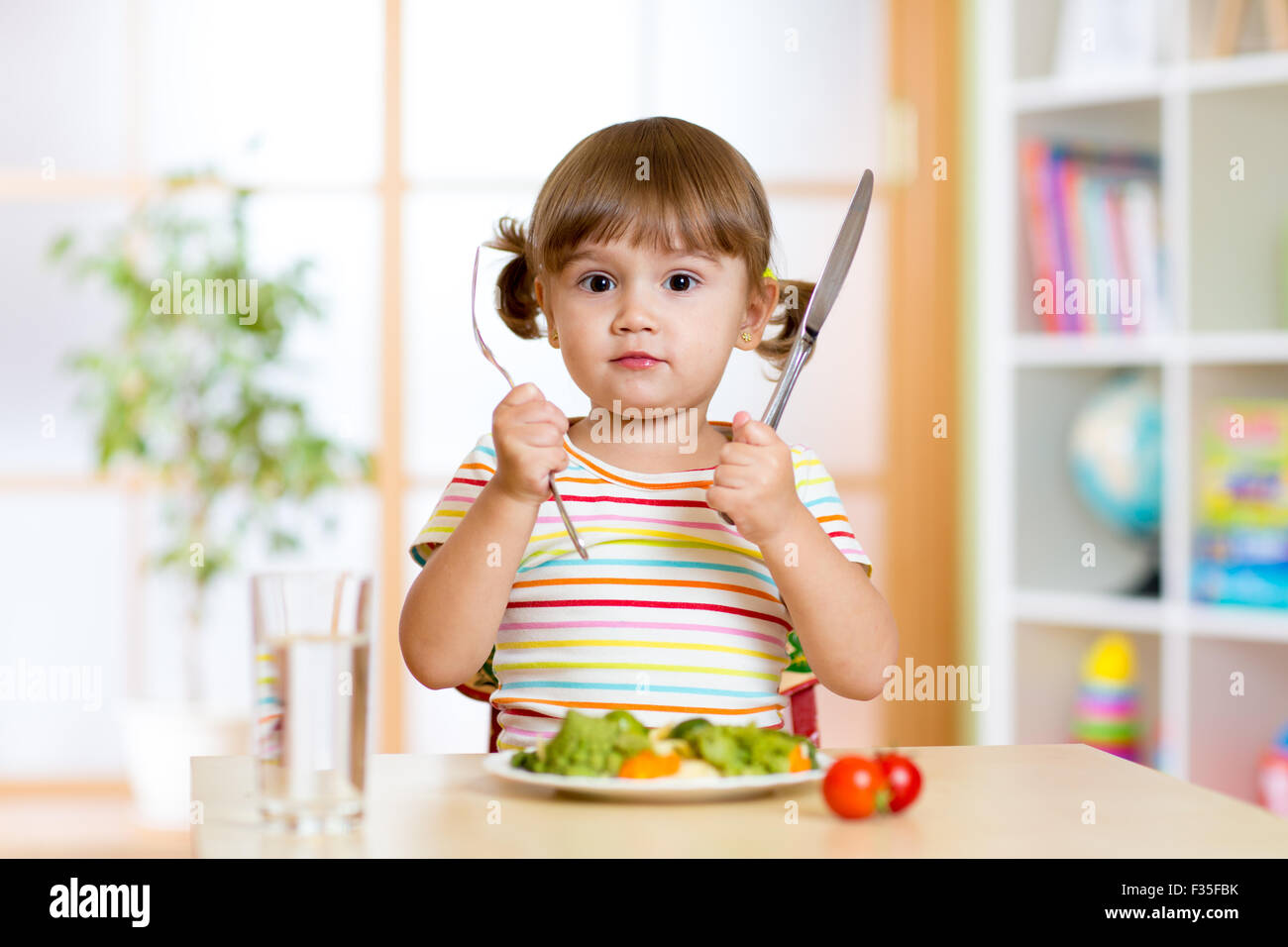 kleines Mädchen mit Gabel und Messer bereit, Essen Stockfoto