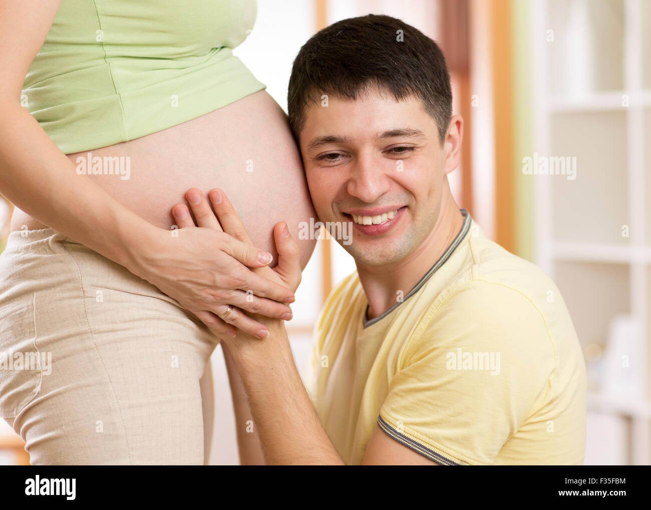 Porträt eines Mannes, den Bauch seiner Frau hören Stockfoto