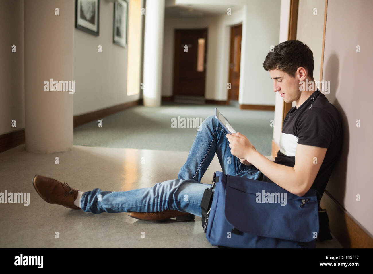Männliche Schüler mit digital-Tablette von Mauer sitzen Stockfoto