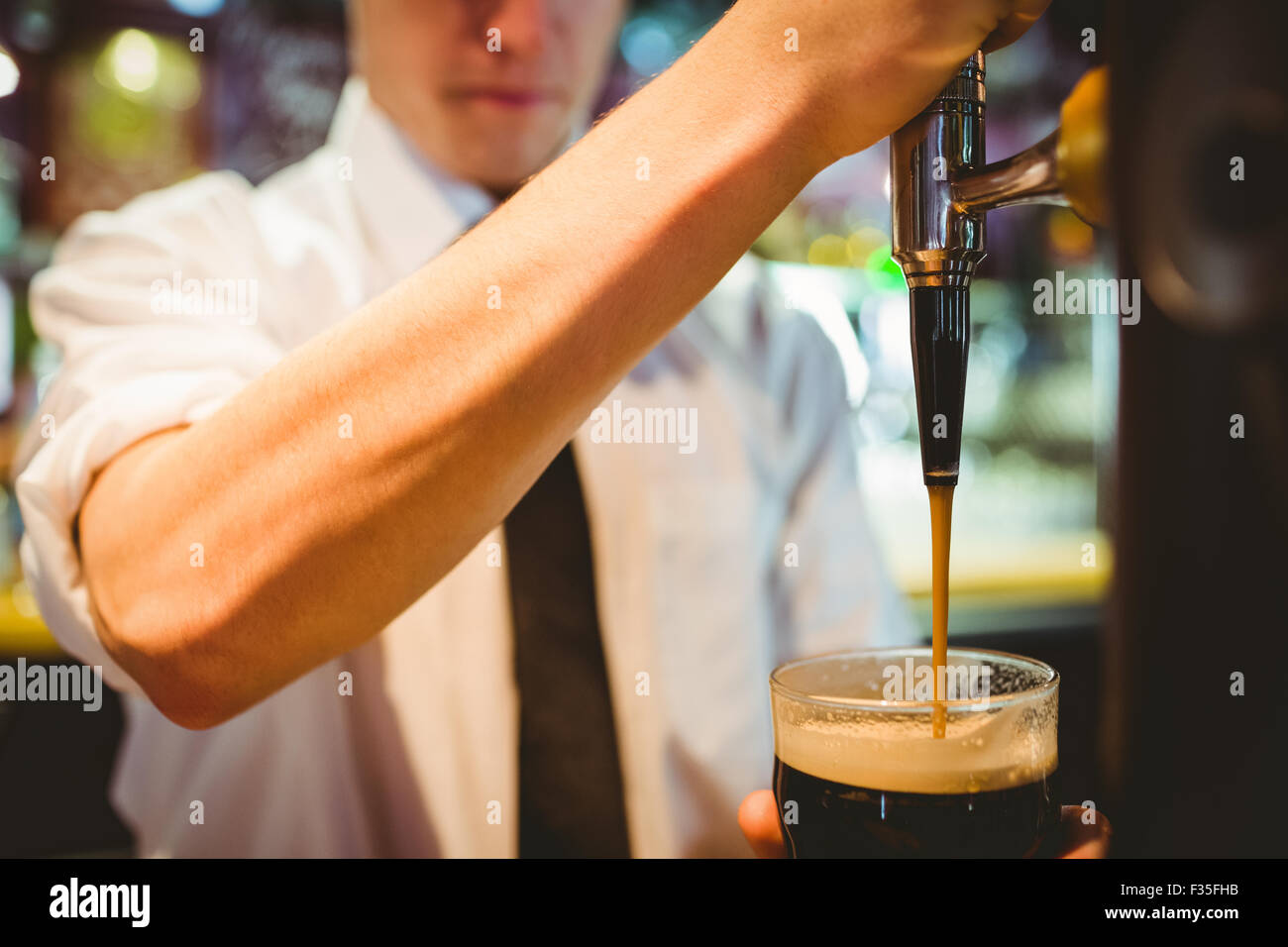 Barkeeper hält Bierglas unter Dispenser Hahn Stockfoto