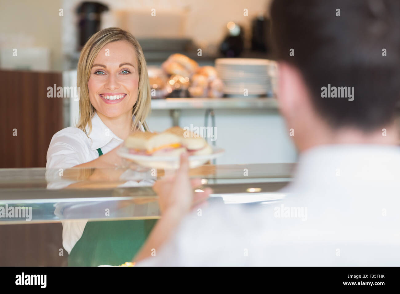 Glücklich weiblichen Ladenbesitzer Sandwich Kunden zu geben Stockfoto