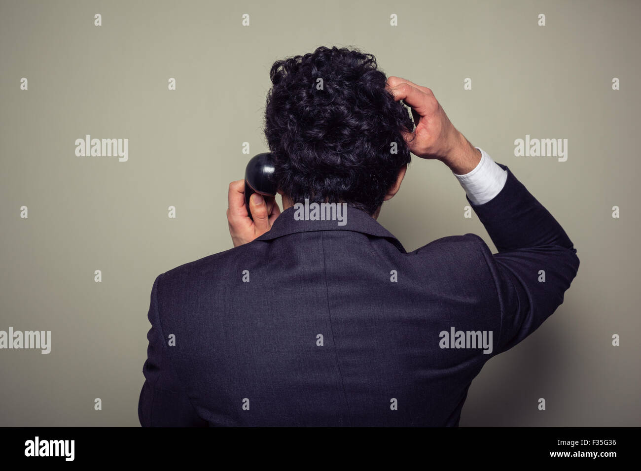 Rückansicht eines verwirrten Geschäftsmann auf dem Handy, kratzte sich am Kopf Stockfoto