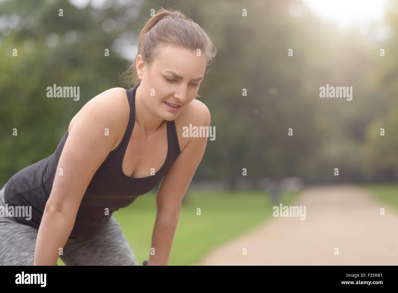 Eine junge Frau ruhen nach ihre körperliche Bewegung im Freien im Park, mit der Sonne geben schöne Fackeln mit Textfreiraum Stockfoto