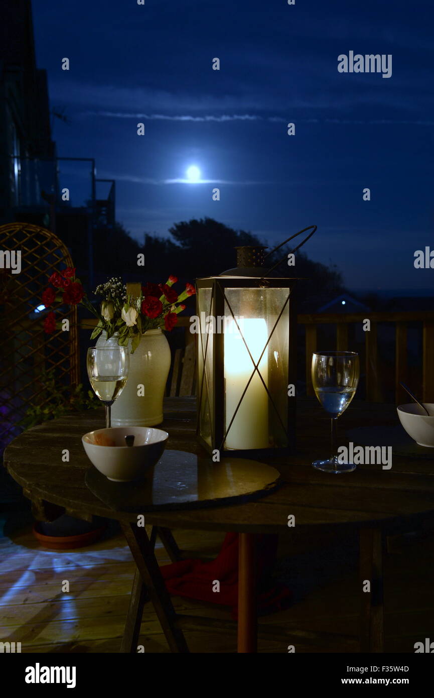 Silbrig Mondaufgang über Kerze beleuchtet Abendessen im freien Stockfoto