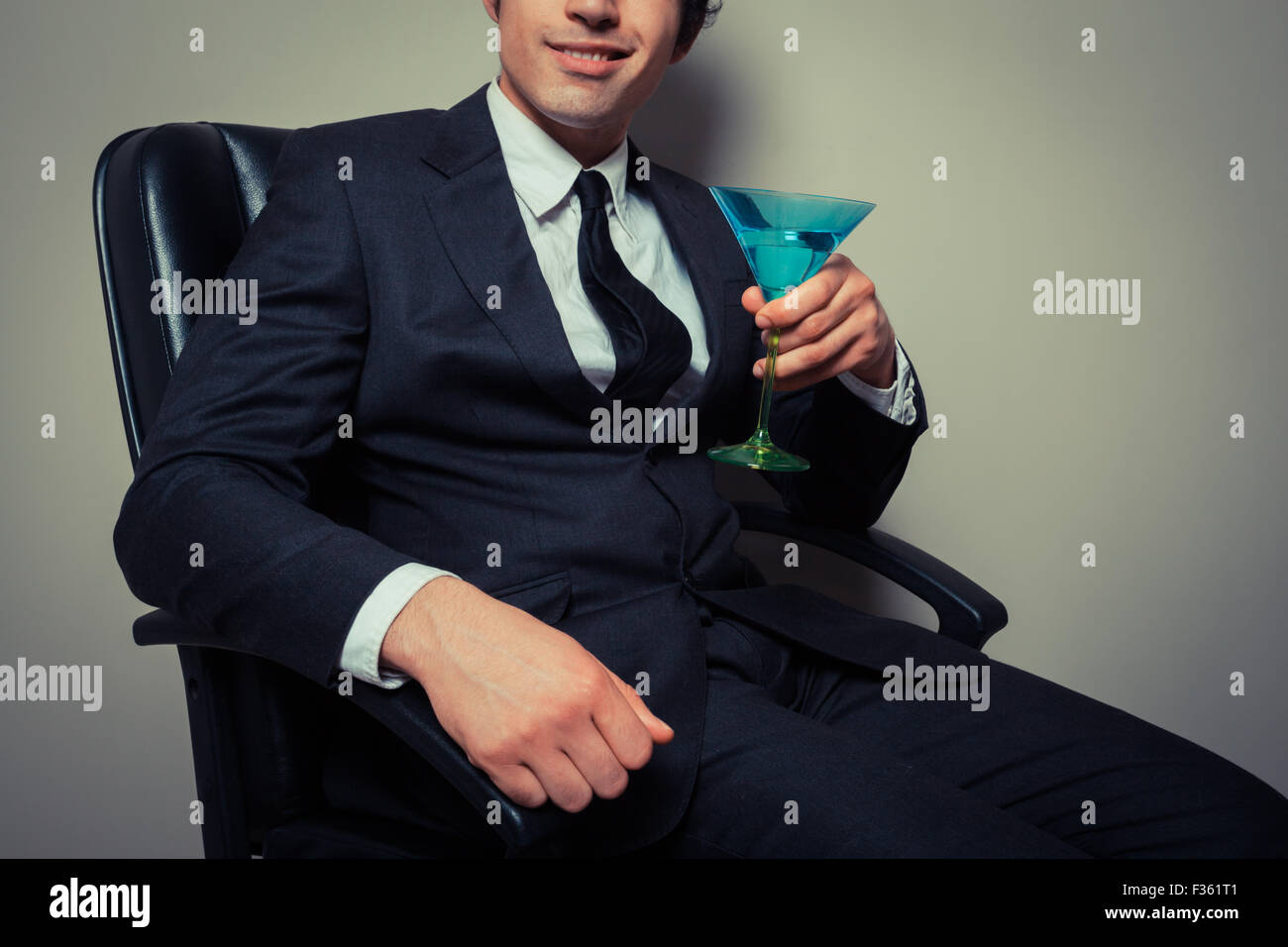 Junger Geschäftsmann, sitzen in einem Bürostuhl mit einem cocktail Stockfoto
