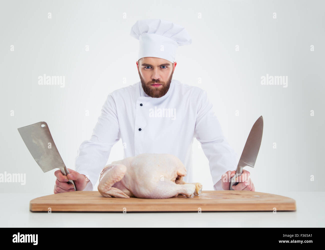 Porträt eines schweren männlichen Chef-Kochs stehend mit Messer und Huhn auf den Tisch, die isoliert auf weißem Hintergrund Stockfoto