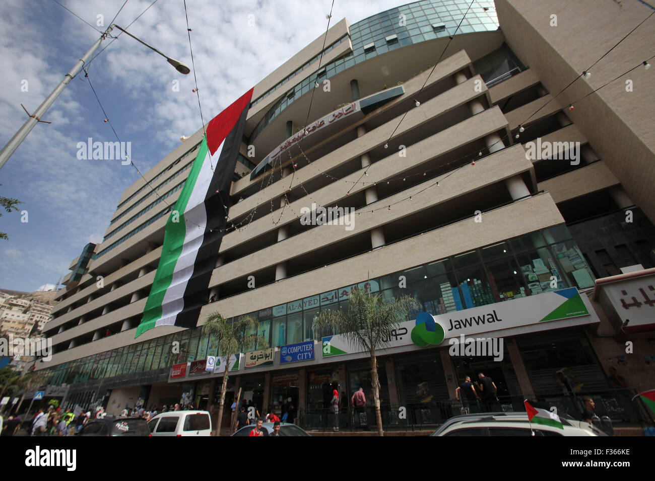 Nablus, Westjordanland, Palästinensische Gebiete. 30. Sep, 2015. Palästinenser Fuß Vergangenheit ihrer Nationalflagge an einem Gebäude während eines Ereignisses gehängt, der palästinensische Präsident Mahmoud Abbas in der West Bank von Nablus am 30. September 2015 zu unterstützen. Abbas hat eine knallharte Kritik an angeblichen Verletzungen des 20-Jahr-alten Osloer Abkommen Israel verteilt und anschließende vor seiner Rede vor der UN-Generalversammlung in New York später Mittwoch Kreditverträge: Nedal Eshtayah/APA Bilder/ZUMA Draht/Alamy Live News Stockfoto