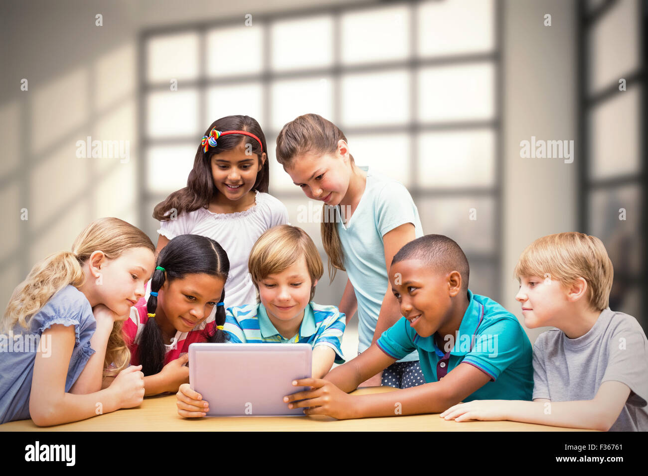 Zusammengesetztes Bild der niedlichen Schülerinnen und Schüler mit Tablet-PC in der Bibliothek Stockfoto
