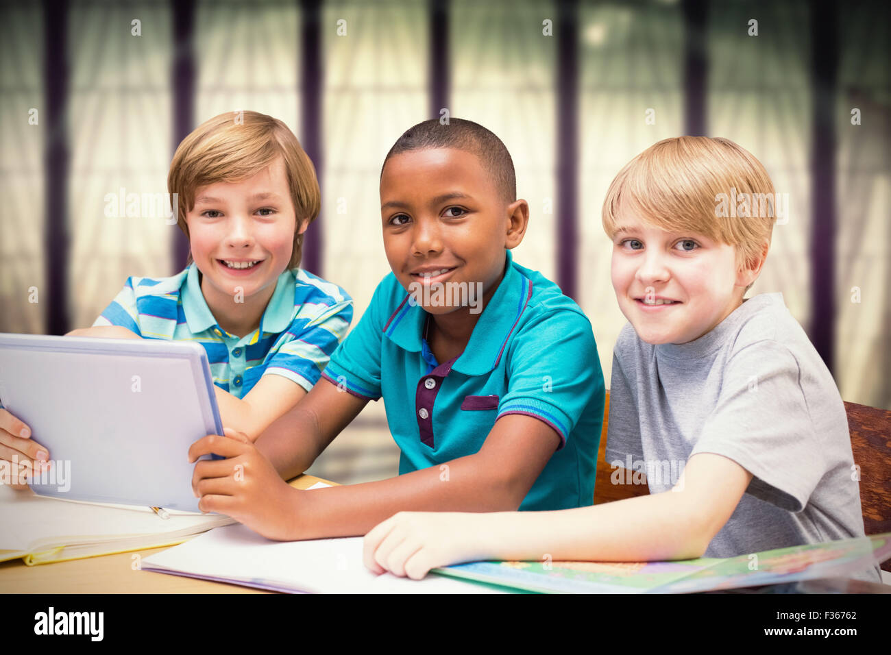 Zusammengesetztes Bild der niedlichen Schülerinnen und Schüler mit Tablet-PC in der Bibliothek Stockfoto