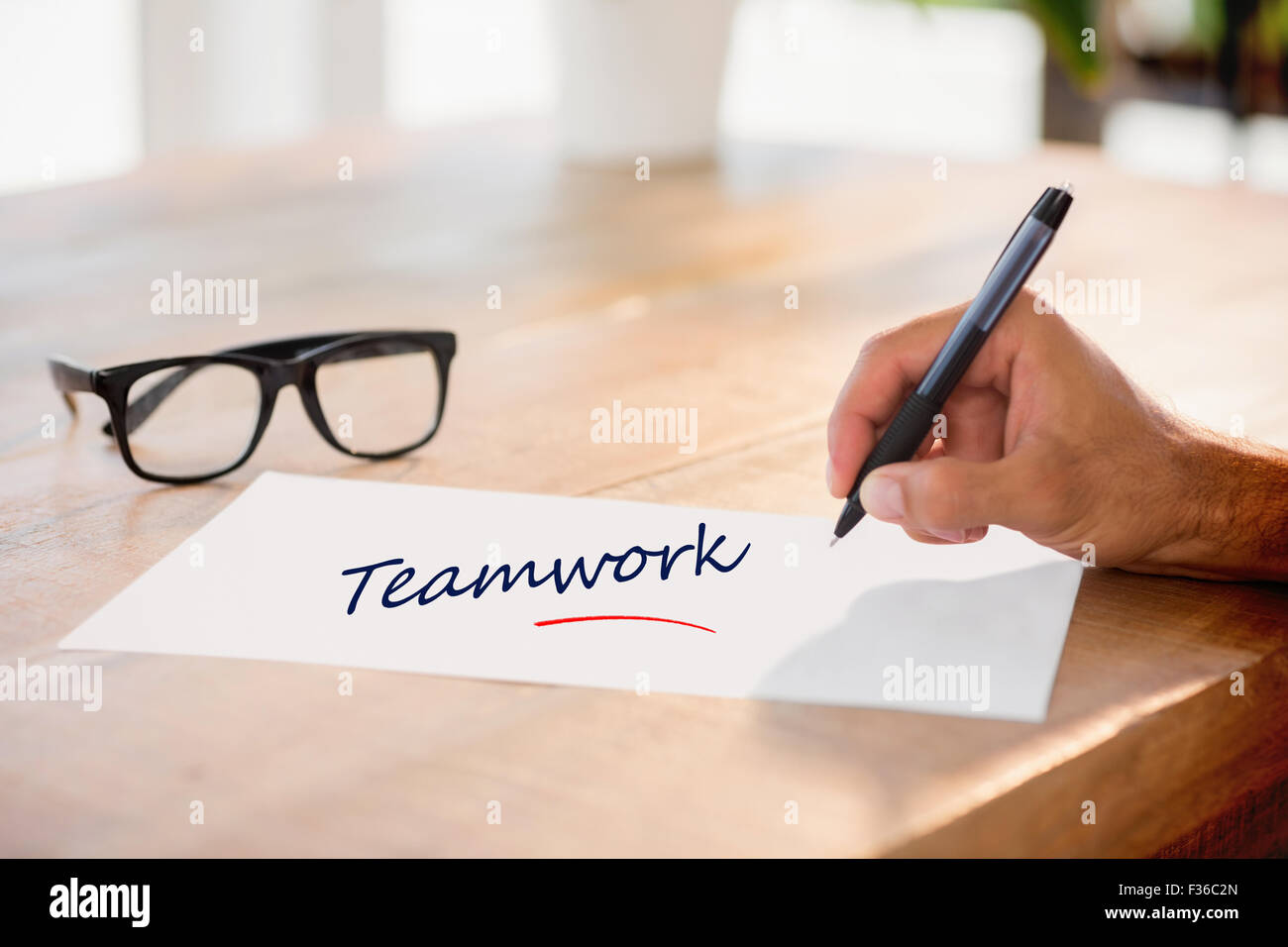 Teamwork gegen Seitenansicht der Handschrift auf weißen Seite auf Arbeitstisch Stockfoto