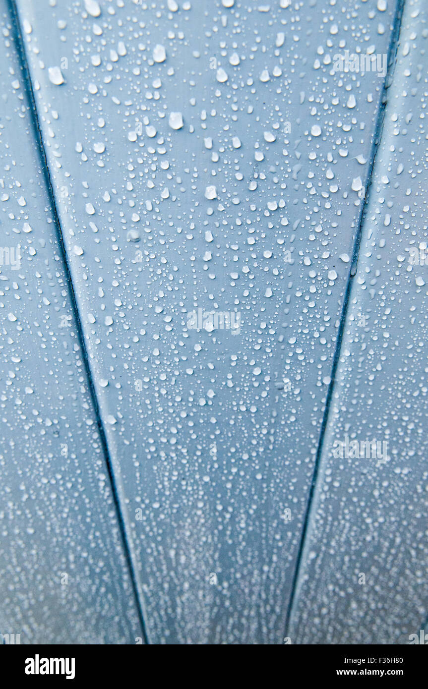 Seitlicher Blick auf Regen Tropfen rannen eine blau lackierte Oberfläche Stockfoto