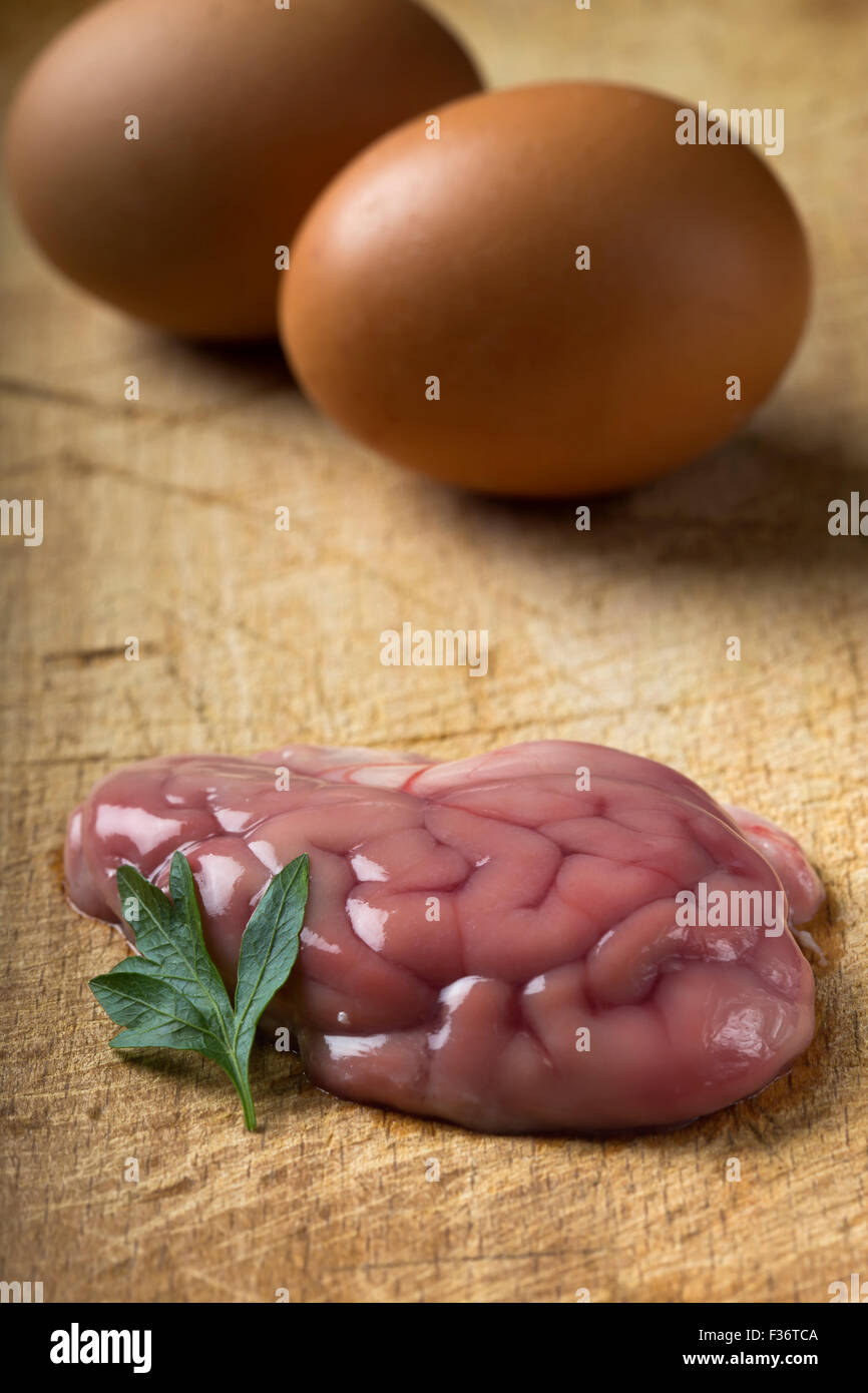 Schweinefleisch-Gehirn über Holz Hintergrund mit zwei Eiern Stockfoto